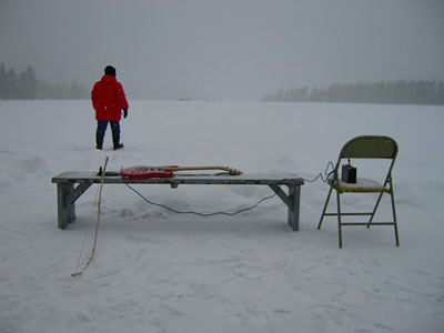 Figure on lake with guitar on bench to foreground